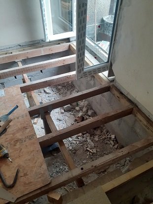 Exposed floor joists during replacement work; work in progress.