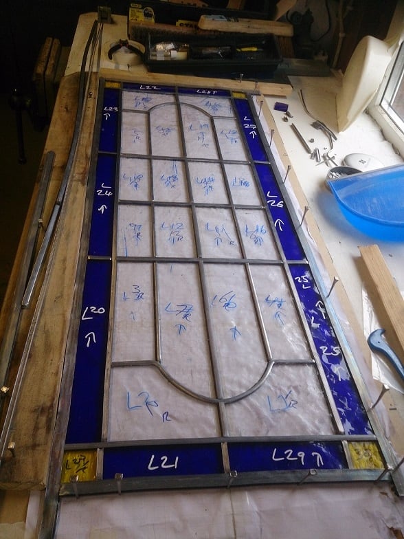A long stained-glass panel laid out on its working pattern.