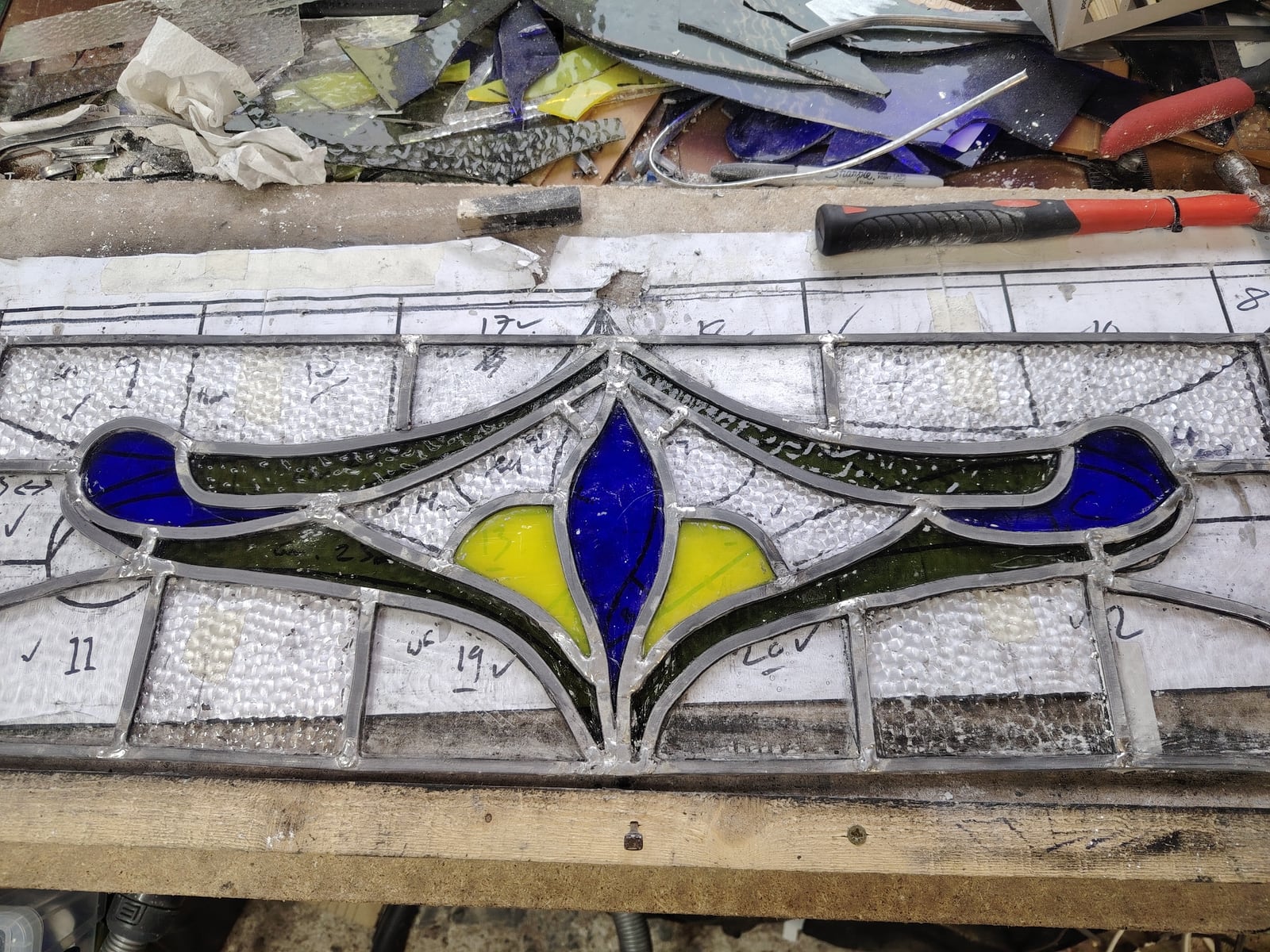 A floral stained-glass panel being assembled on the workbench.